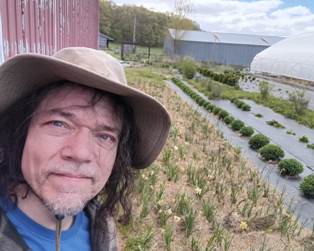Paul wearing a hat outside in the middle of a small farm