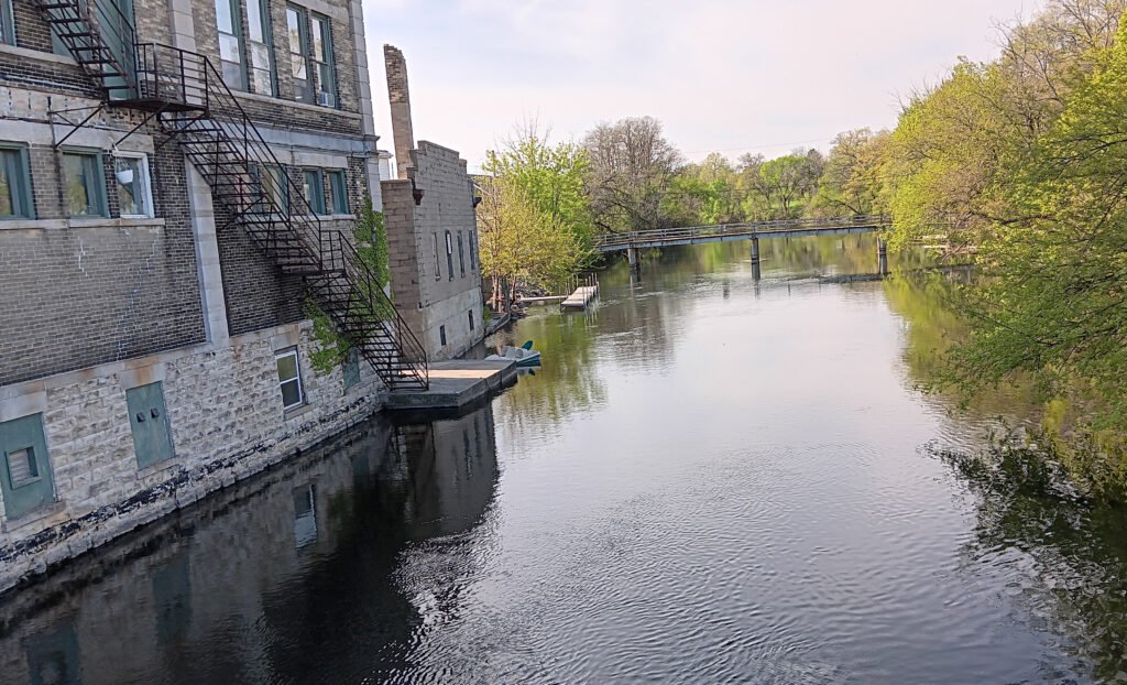 Downtown brick building with long fire escape ending at riverside dock with paddleboat